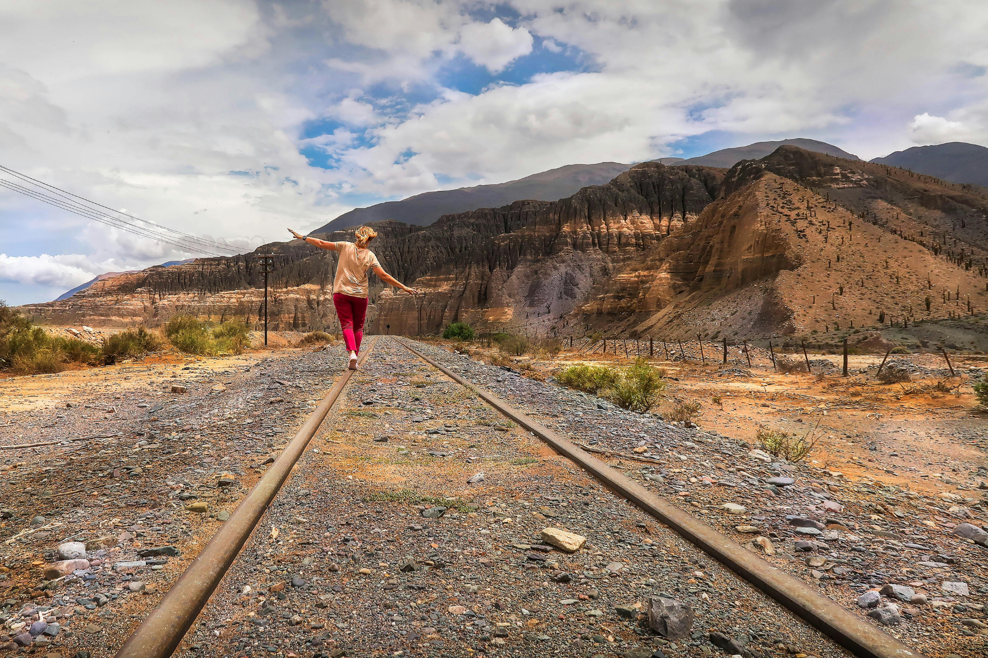Vrouw loopt in balans over spoorlijn – symbool voor levenspad, innerlijke kracht en het proces van herstel